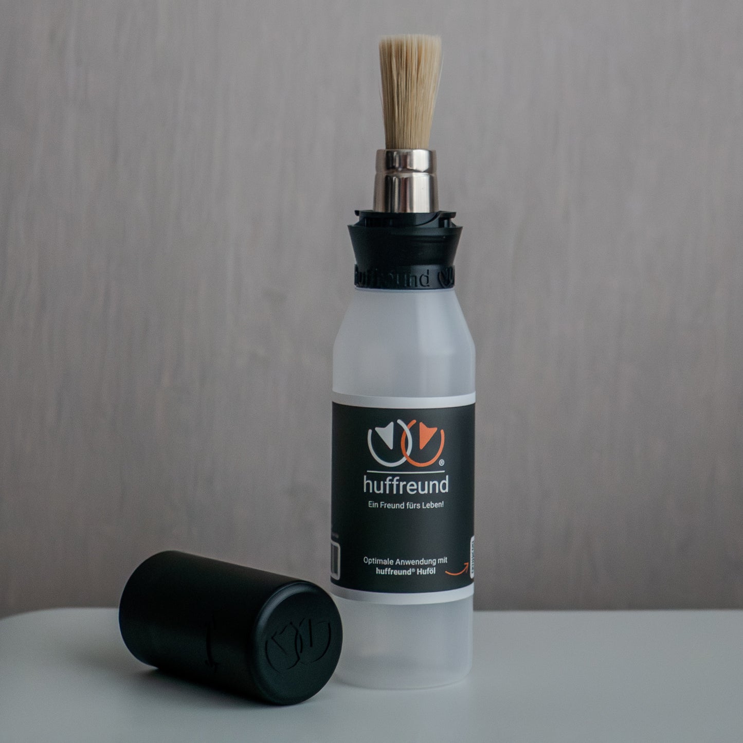 huffreund-Pinselflasche Compact für Huföl auf Pferdehufen steht vor schlichtem Hintergrund zu Präsentationszwecken.
