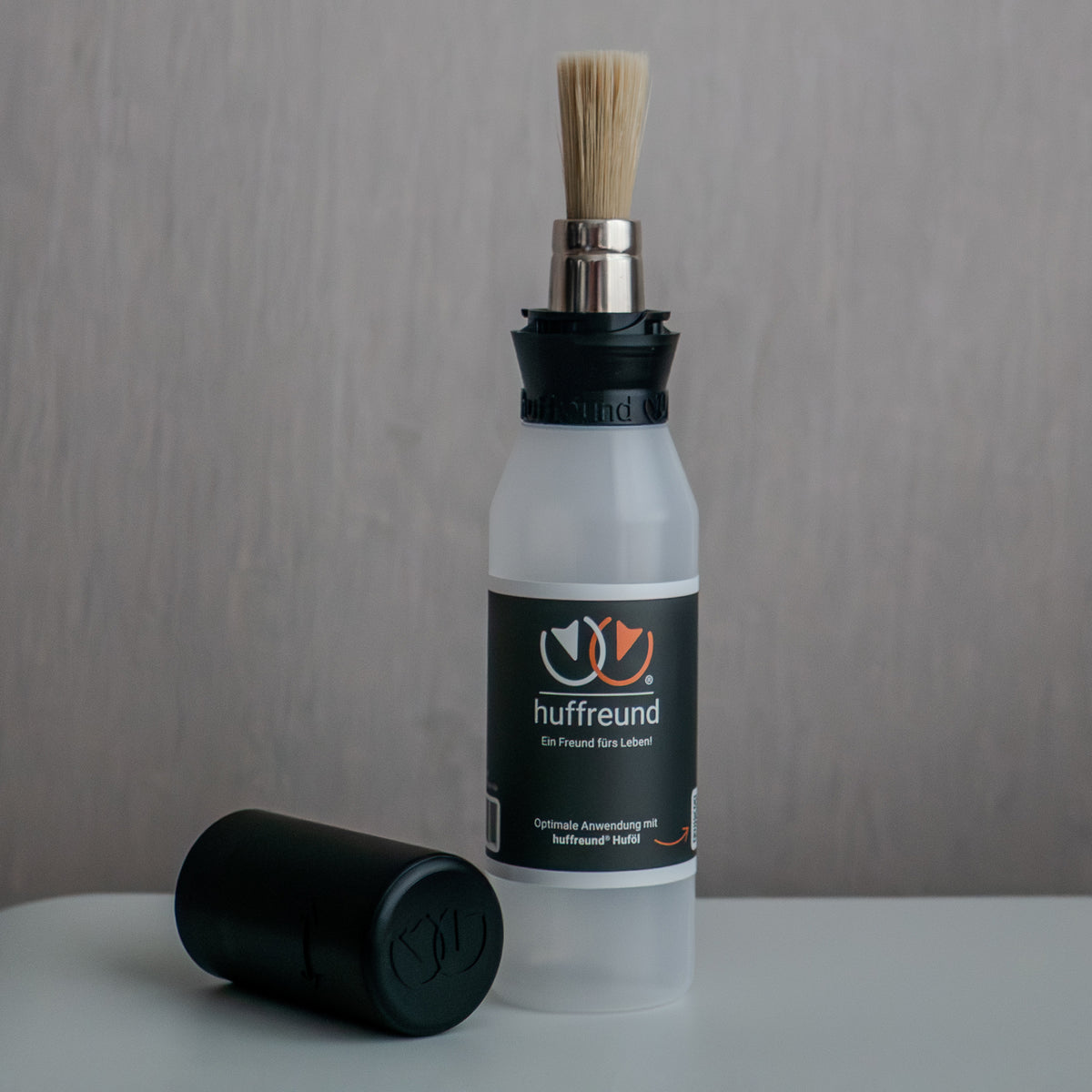 huffreund-Pinselflasche Compact für Huföl auf Pferdehufen steht vor schlichtem Hintergrund zu Präsentationszwecken.