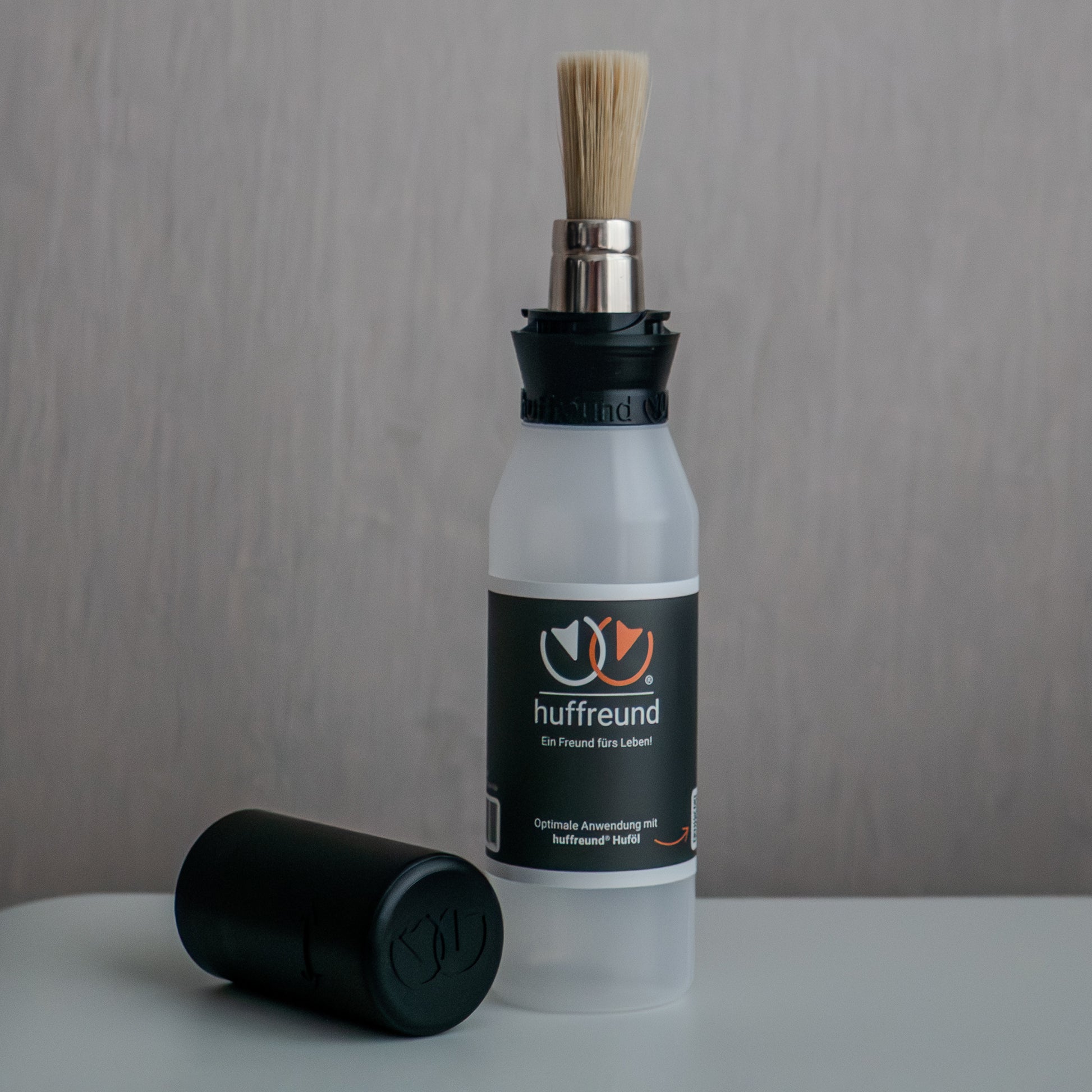huffreund-Pinselflasche Compact für Huföl auf Pferdehufen steht vor schlichtem Hintergrund zu Präsentationszwecken.