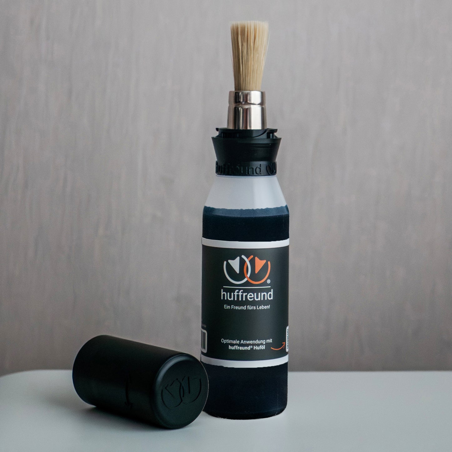 huffreund-Pinselflasche Compact+ inkl. Huföl für Pferdehufe steht vor schlichtem Hintergrund zu Präsentationszwecken.