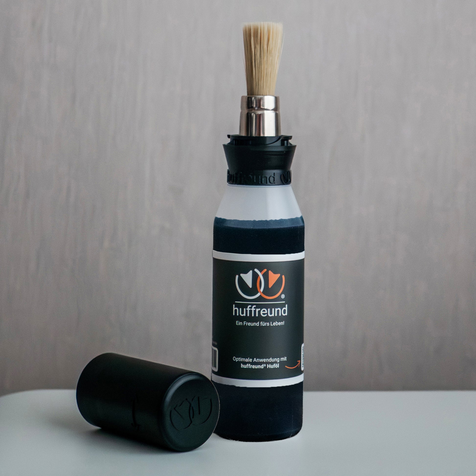 huffreund-Pinselflasche Compact+ inkl. Huföl für Pferdehufe steht vor schlichtem Hintergrund zu Präsentationszwecken.