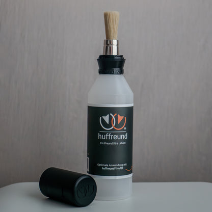 huffreund-Pinselflasche Pro für Huföl auf Pferdehufen steht vor schlichtem Hintergrund zu Präsentationszwecken.