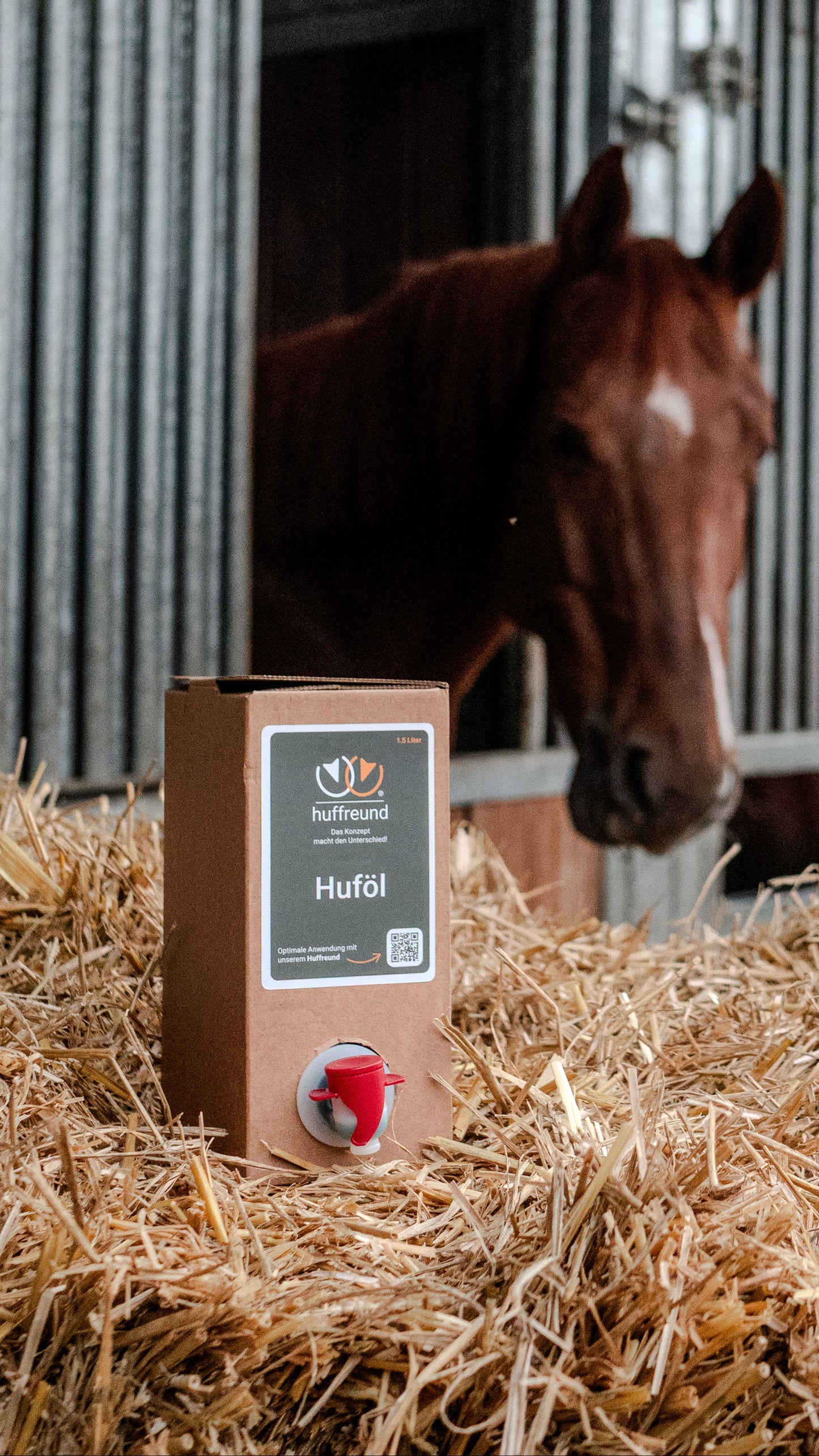 huffreund-Huföl für Pferdehufe in Bag-In-Box 1,5L auf Stroh vor Pferdekopf im Hintergrund. 